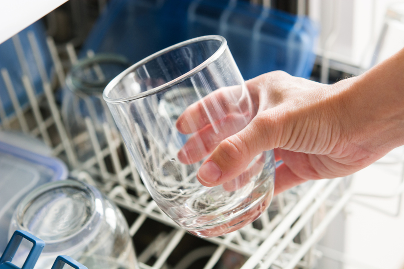 Woman taking a glass out of the dishwasher